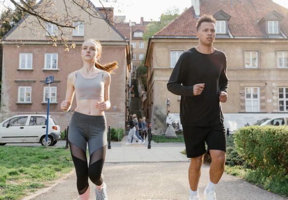 Two young adults jogging on a city path, showcasing an active lifestyle in an urban environment.