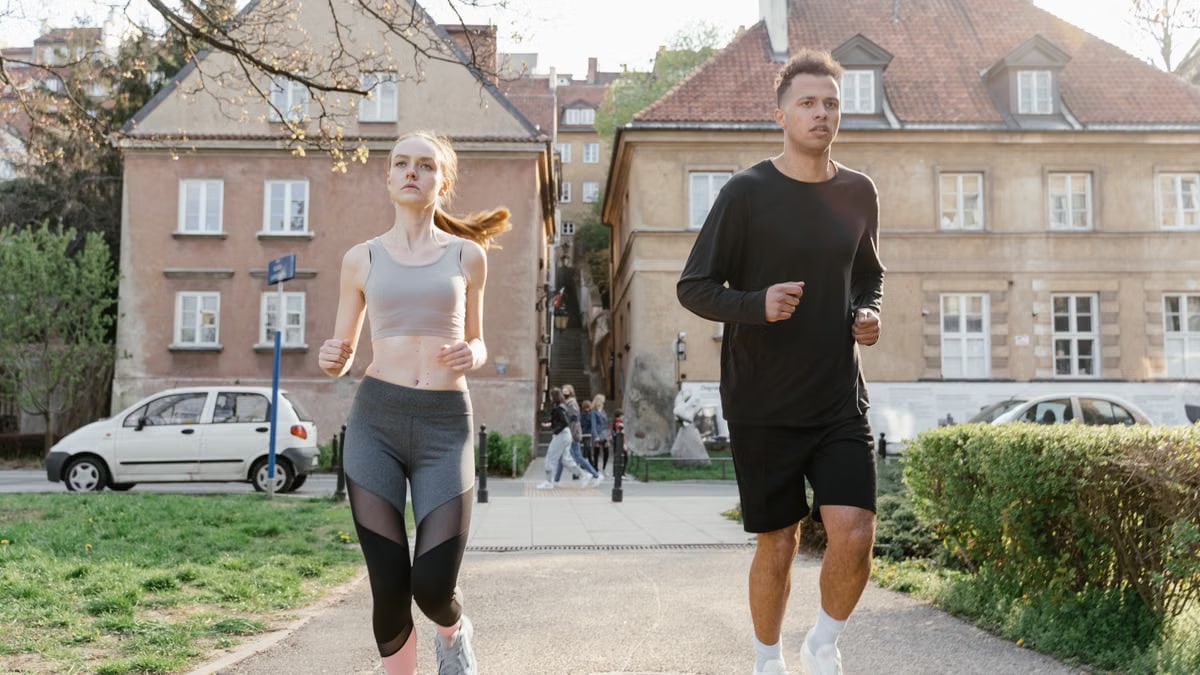 Two young adults jogging on a city path, showcasing an active lifestyle in an urban environment.